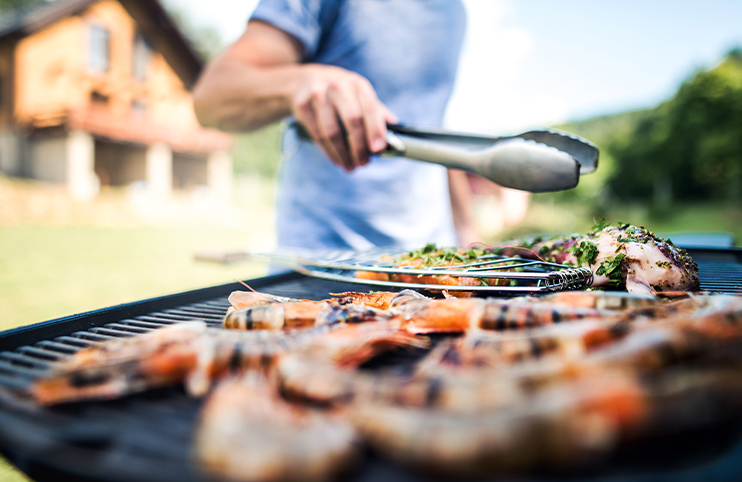 Unrecognizable man cooking seafood on a barbecue grill in the backyard.