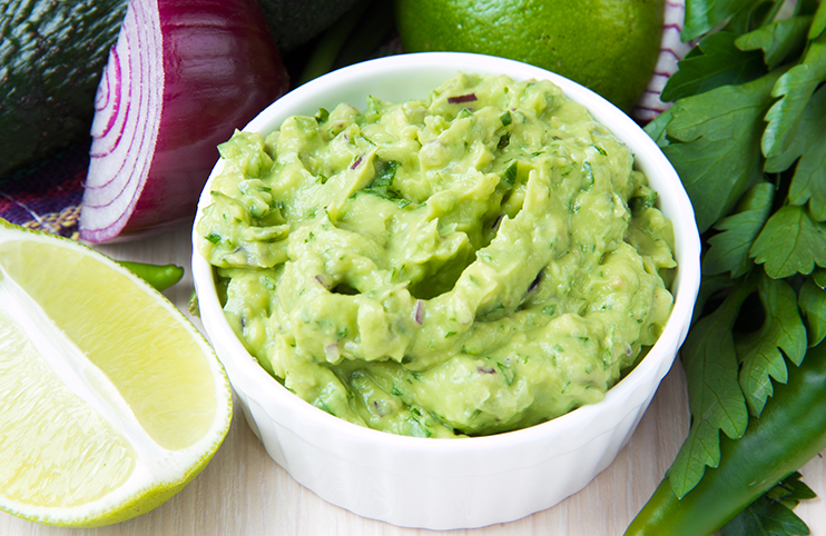 Green Mexican guacamole dip with avocado, lime, parsley and red onions
